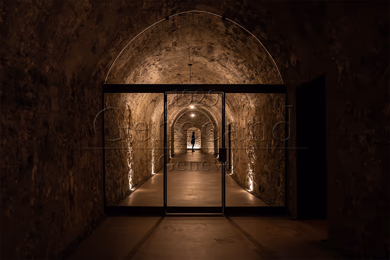Beleuchteter Gewölbekeller der La Corne à Vin mit Blick durch eine Glastür