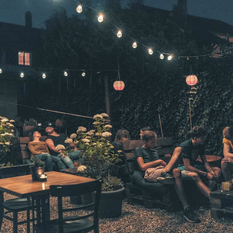 Begrünter Innenhof mit Sitzplätzen und Lichterkette am Abend