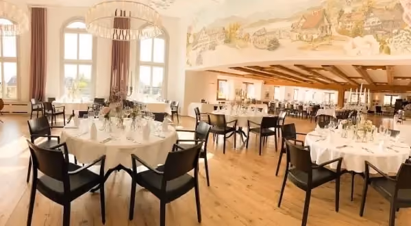 Löwen-Saal mit festlich gedeckten runden Tischen und grossen Fenstern