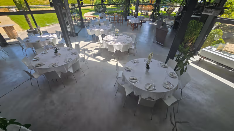 Lichtdurchfluteter Wintergarten von LF22 mit gedeckten runden Tischen