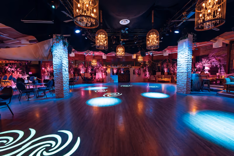 Tanzfläche im Dance Inn mit Kronleuchtern, Steinpfeilern und farbiger Beleuchtung