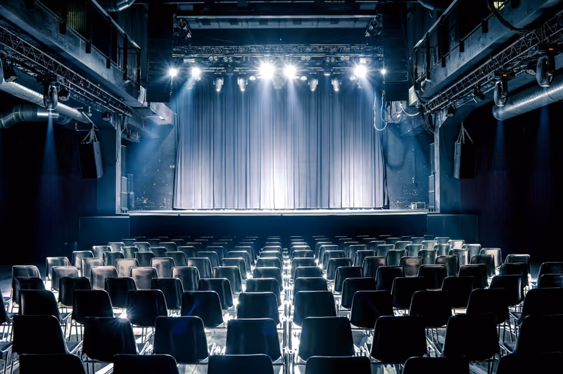 Saal des Komplex 457 mit Stuhlreihen, Bühne sowie Licht- und Tontechnik